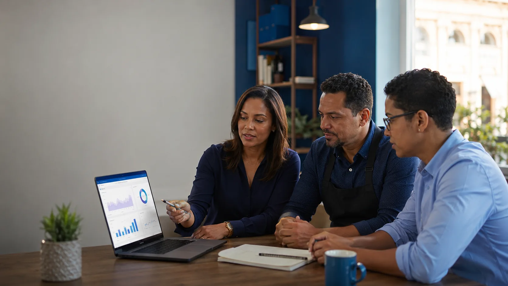 Tres profesionales dominicanos analizan juntos un panel de indicadores en una laptop durante una reunión de trabajo.